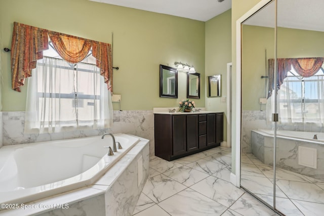 full bath with marble finish floor, a garden tub, a sink, and double vanity