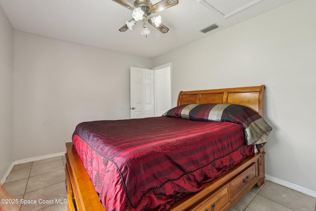 bedroom with light tile patterned floors, attic access, baseboards, visible vents, and a ceiling fan