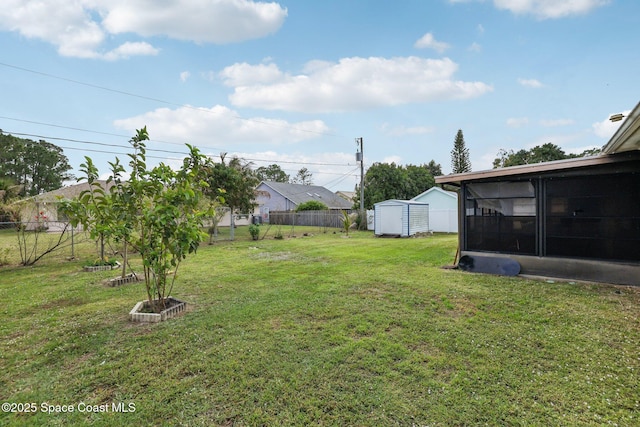 view of yard with an outbuilding, a sunroom, fence, and a storage unit