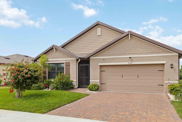 view of front of property with an attached garage, a front yard, decorative driveway, and stucco siding