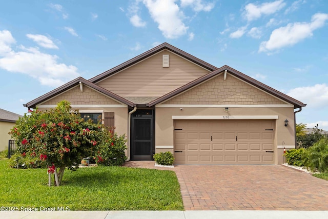 view of front of house with a garage, decorative driveway, a front lawn, and stucco siding