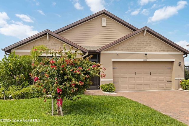 craftsman inspired home featuring a garage, decorative driveway, a front lawn, and stucco siding