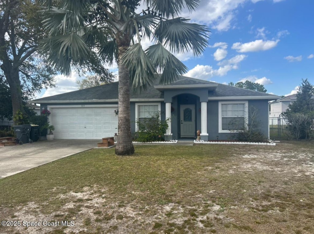 view of front of property with a garage, fence, concrete driveway, stucco siding, and a front lawn