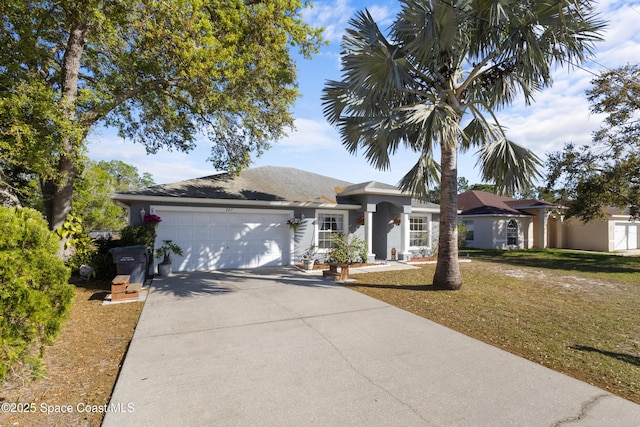 single story home featuring concrete driveway, a garage, a front yard, and stucco siding