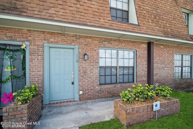 property entrance with brick siding and roof with shingles