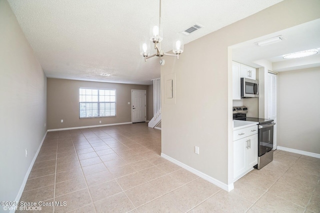 kitchen with light tile patterned floors, stainless steel appliances, visible vents, white cabinetry, and a chandelier