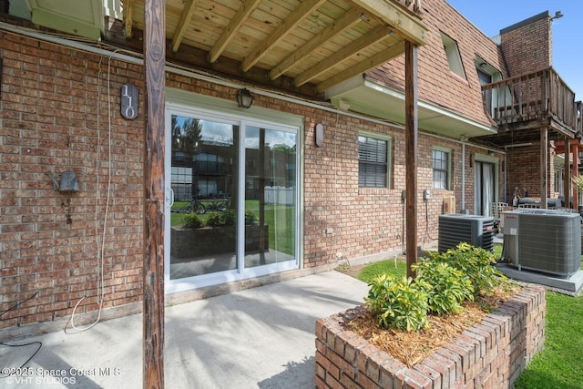 view of exterior entry with central AC and brick siding