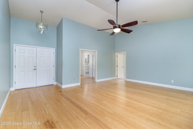 interior space featuring visible vents, light wood-style floors, high vaulted ceiling, baseboards, and ceiling fan with notable chandelier