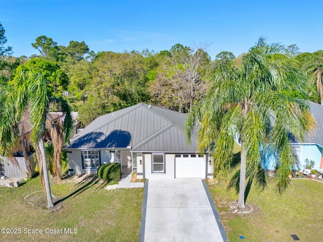 ranch-style home featuring concrete driveway, an attached garage, metal roof, fence, and a front lawn