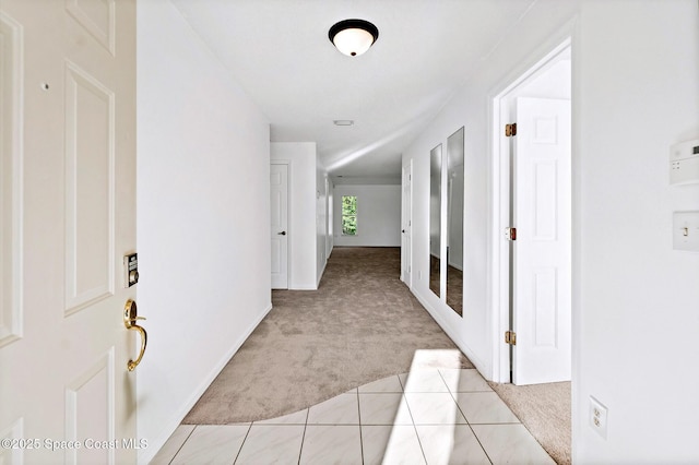 hall with light carpet and light tile patterned flooring