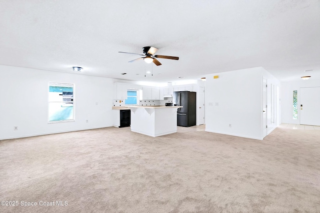 unfurnished living room featuring ceiling fan, baseboards, and light colored carpet