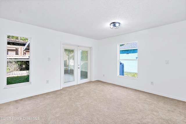 carpeted spare room featuring a textured ceiling, french doors, and baseboards