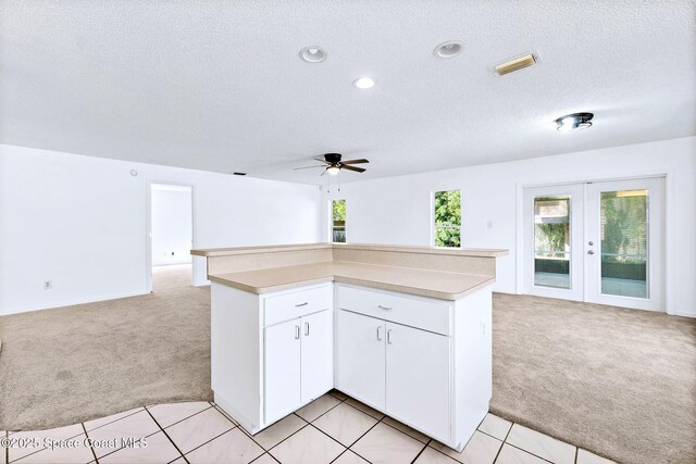 kitchen with open floor plan, a center island, visible vents, and light colored carpet