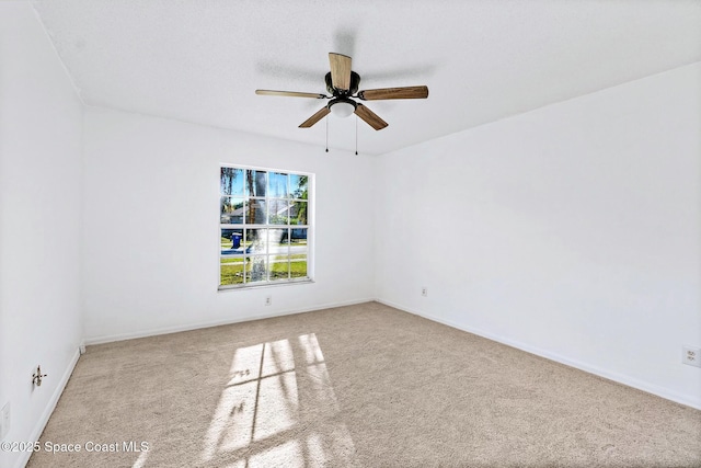 carpeted empty room featuring a ceiling fan and baseboards