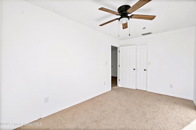 spare room featuring a ceiling fan, carpet flooring, visible vents, and baseboards