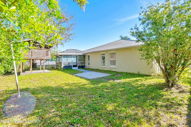 back of house featuring a sunroom, metal roof, fence, a yard, and stucco siding