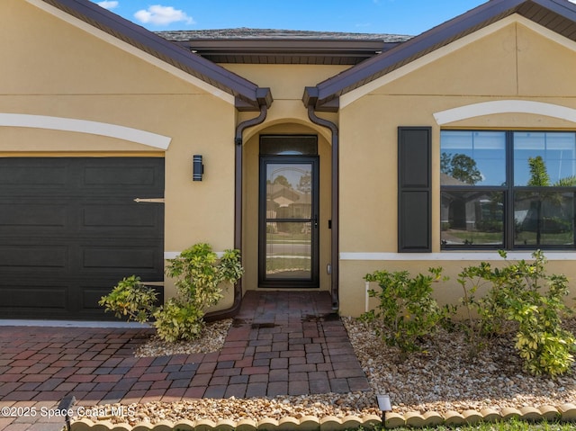 entrance to property featuring a garage and stucco siding