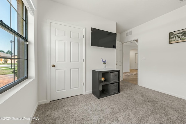 carpeted living area featuring arched walkways, visible vents, and baseboards