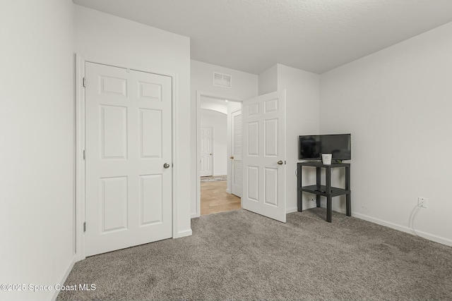 unfurnished bedroom featuring baseboards, visible vents, and carpet flooring