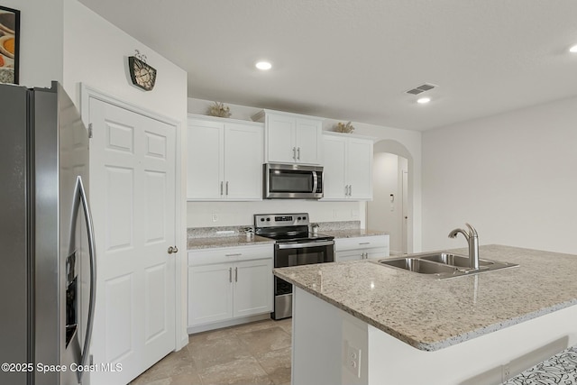 kitchen featuring arched walkways, stainless steel appliances, a sink, visible vents, and white cabinetry