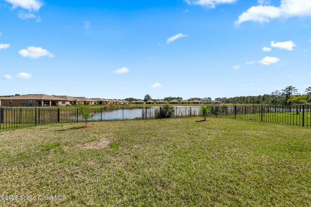 view of yard with a residential view, a water view, and fence