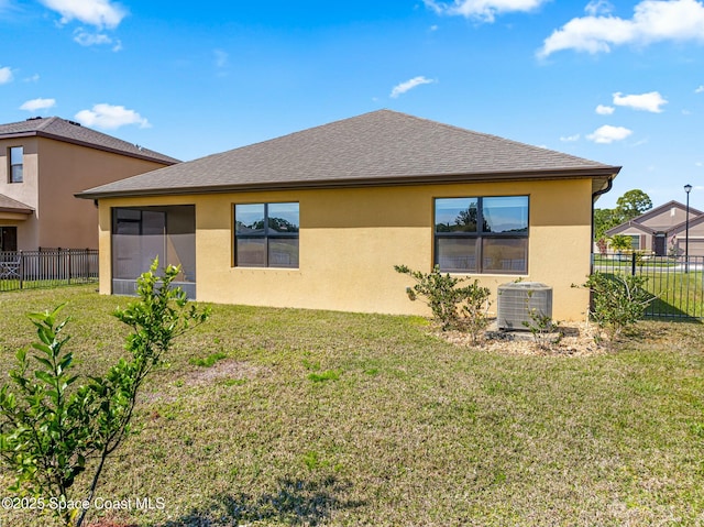 back of property with roof with shingles, stucco siding, a lawn, central AC unit, and fence