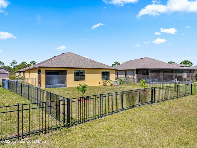 rear view of property featuring a yard, a fenced backyard, a sunroom, and stucco siding