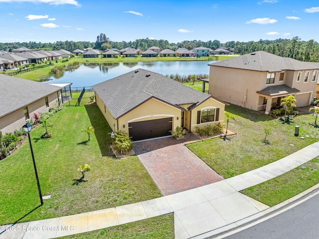 view of front of property featuring a residential view, decorative driveway, a water view, and a front lawn