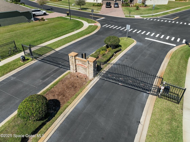 view of street featuring curbs, a gated entry, sidewalks, and a gate