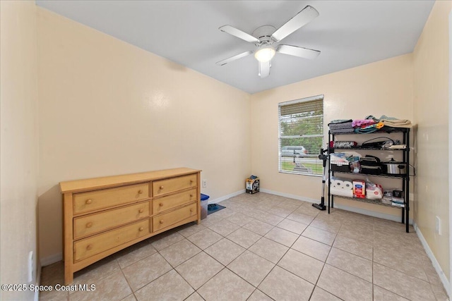 workout room with light tile patterned floors, a ceiling fan, and baseboards