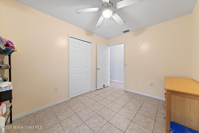 unfurnished bedroom with a closet, visible vents, a ceiling fan, light tile patterned flooring, and baseboards