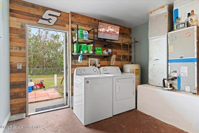 clothes washing area with water heater, laundry area, washing machine and dryer, and wooden walls