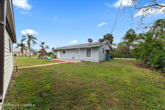 back of property with a lawn, a fenced backyard, a patio area, a playground, and stucco siding