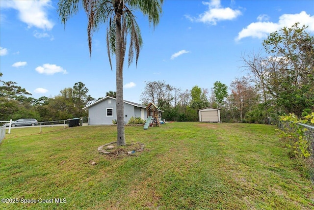 view of yard with fence, a playground, and an outbuilding