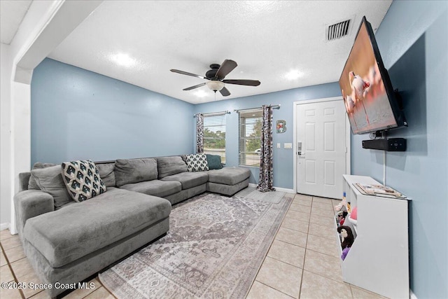 living room with light tile patterned floors, baseboards, visible vents, a ceiling fan, and a textured ceiling