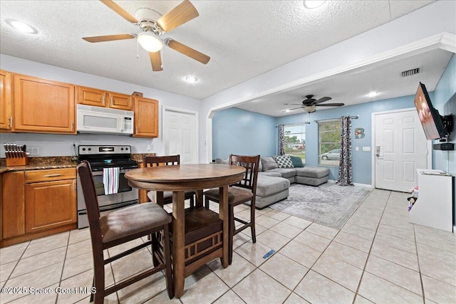 dining space featuring light tile patterned floors, a textured ceiling, visible vents, and a ceiling fan