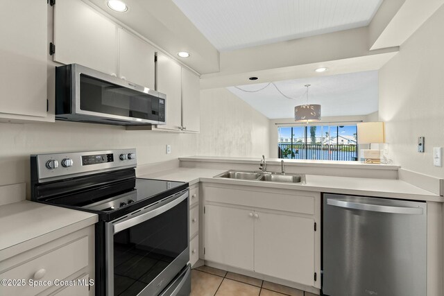 kitchen featuring light tile patterned floors, light countertops, appliances with stainless steel finishes, white cabinetry, and a sink