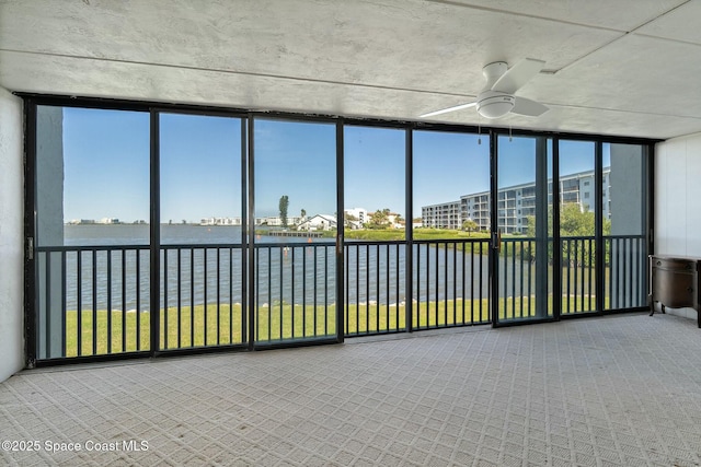 unfurnished sunroom with a water view and a ceiling fan