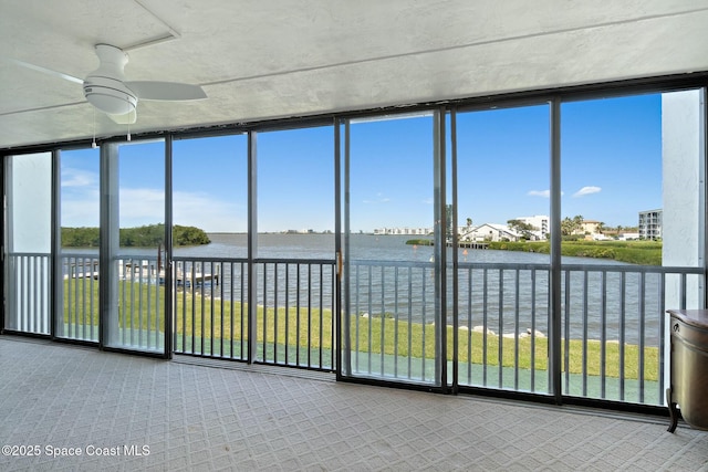 unfurnished sunroom with a water view, a wealth of natural light, and a ceiling fan