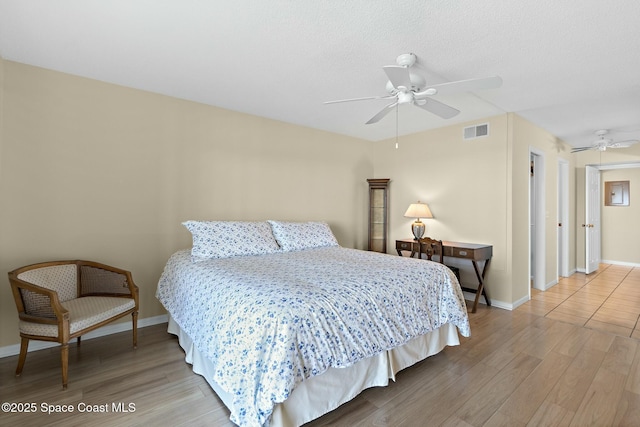 bedroom with baseboards, visible vents, ceiling fan, and wood finished floors