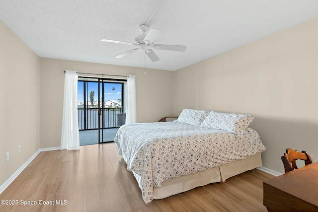 bedroom featuring access to exterior, light wood-style floors, a textured ceiling, and baseboards