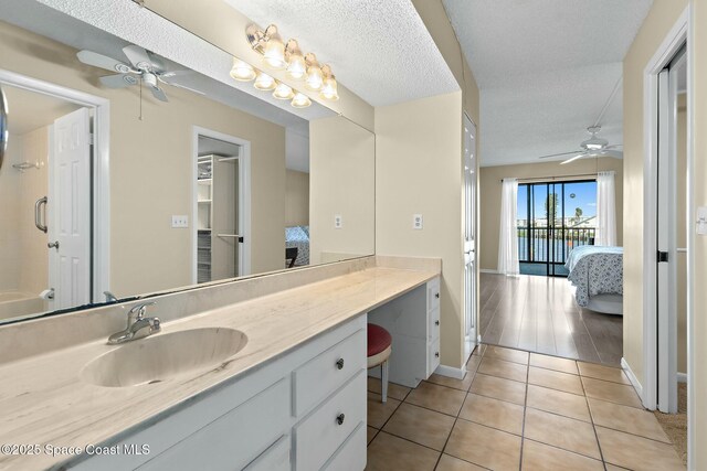 ensuite bathroom with a ceiling fan, a textured ceiling, ensuite bath, vanity, and tile patterned flooring