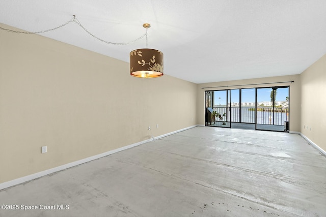 unfurnished room featuring concrete floors and baseboards