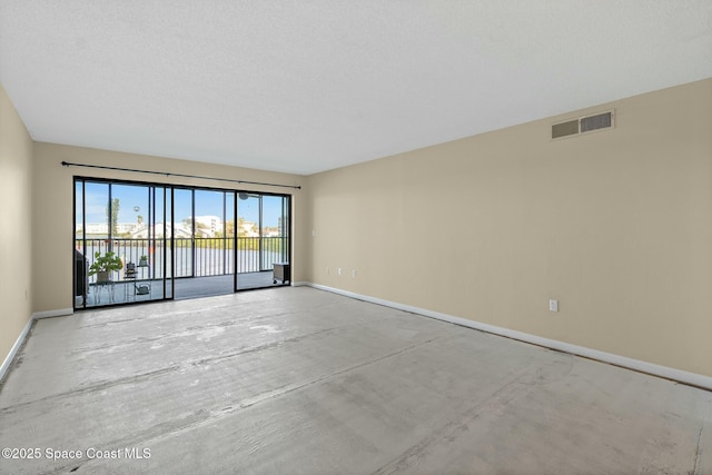 spare room featuring visible vents, concrete floors, and baseboards