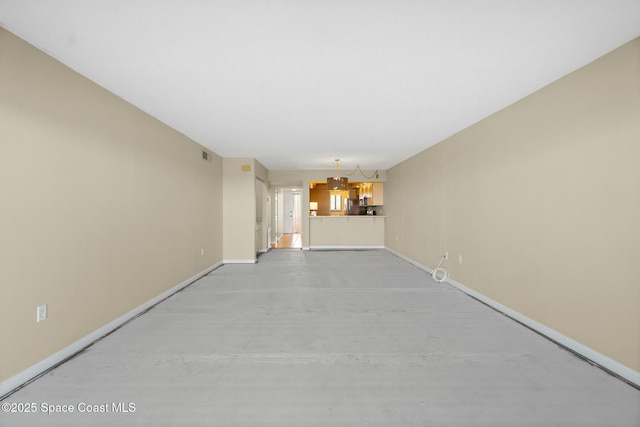 unfurnished living room featuring a chandelier, visible vents, and baseboards