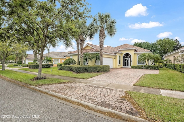 mediterranean / spanish house featuring stucco siding, a front lawn, a garage, a tiled roof, and decorative driveway