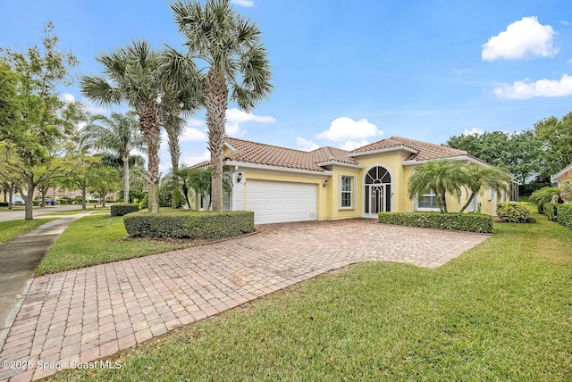 mediterranean / spanish house featuring stucco siding, a tile roof, decorative driveway, a front yard, and a garage