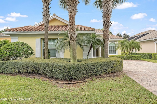 mediterranean / spanish-style house with stucco siding, a tiled roof, and a front yard