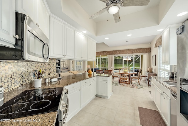 kitchen with light tile patterned floors, a peninsula, white cabinets, appliances with stainless steel finishes, and tasteful backsplash