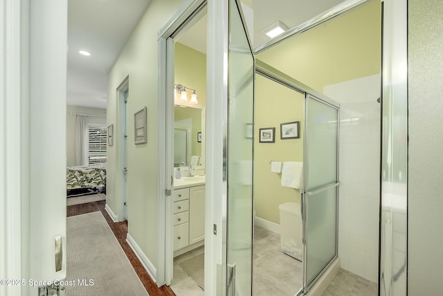 bathroom featuring vanity, a shower stall, baseboards, and connected bathroom